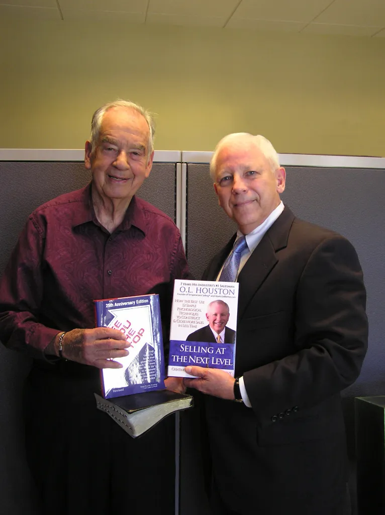 Two men presenting a book in a professional setting